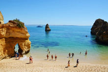 Tourists at scenic Camilo Beach (Praia do Camilo) at Algarve, Portugal with turquoise sea in background