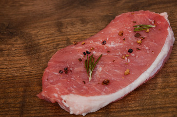 raw pork meat chop steak on the brown wooden table background. rustic kitchen table with copy space.