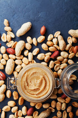 Wall Mural - Peanut butter jar and heap of nuts on rustic table top view.