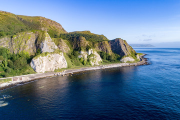 Wall Mural - The eastern coast of Northern Ireland with cliffs and Antrim Coastal Road, a.k.a. Causeway Coastal Route. Aerial view at sunrise