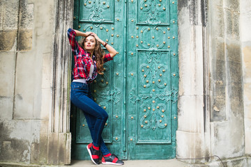 Wall Mural - close up portrait of cute smiling woman on a background of green vintage door wearing casual clothes in summer city