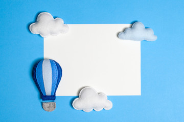 Hot air balloon in blue sky with clouds, frame, copyspace. Hand made felt toys.