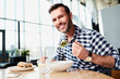 © baranq - Smiling middle-aged man looking at camera while eating lunch in bright modern restaurant