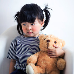 Lovely and innocent asian kid  with teddy looking at something