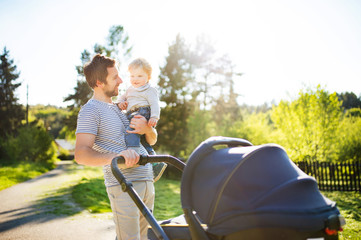 Wall Mural - Father with little son and baby daughter in stroller. Sunny park