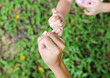 Mother and daughter making a pinkie promise in the green grass garden.