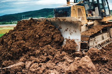 Wall Mural - yellow mini bulldozer working with earth and soil while doing landscaping works on construction site