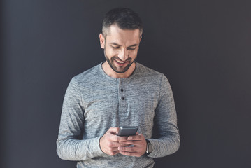 Wall Mural - Delightful manager male is holding smartphone with smile