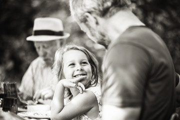 Poster - family lunching in the garden focus on a beautiful little girl