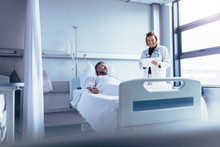 Doctor Attending Sick Patient In Hospital Bed