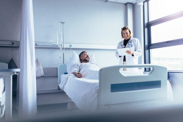 Doctor attending sick patient in hospital bed