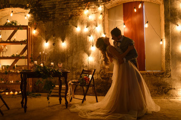 Stylish hipster wedding couple in romantic loft decorations at night