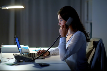 Canvas Print - woman with laptop calling on phone at night office