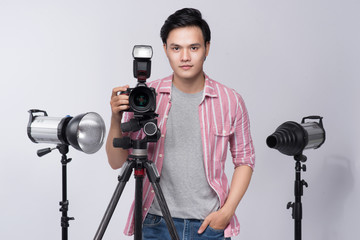 Fototapete - Young asian photographer holding digital camera, while working in studio