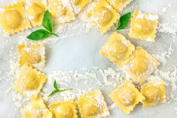 Overhead photo of ravioli with flour and basil leaves