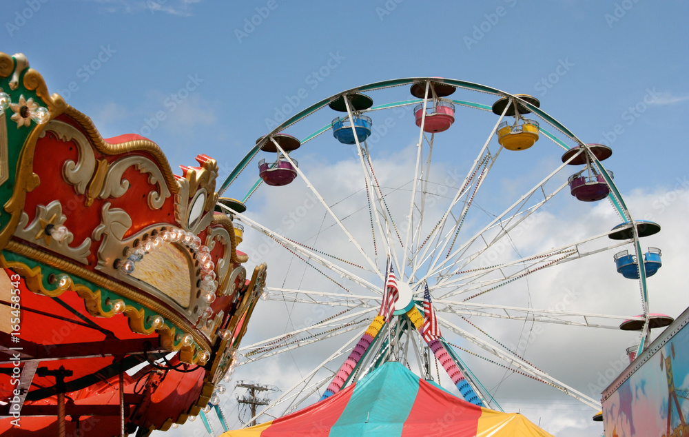 Fair carnival rides and tent top against blue sky. - obrazy, fototapety, plakaty 