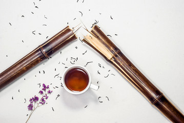 Broken stem of bamboo, purple flowers, lavender, herbarium, dry tea, cup of tea. Flat lay