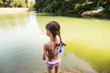 Little girl standing at the lake. Sunny summer.