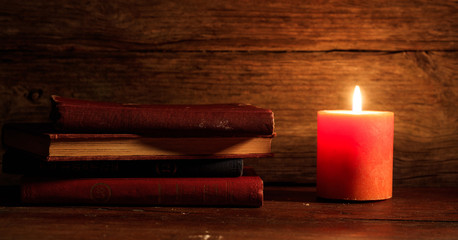 Wall Mural - Vintage books and a candle on wooden background