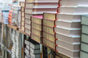 Abstract blurred background of pile of books, textbooks, fiction in book store or in library. Education, school, study, reading fiction concept.