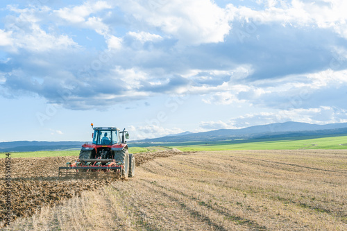agricultural machinery in the foreground carrying out work in the field Obraz na płótnie