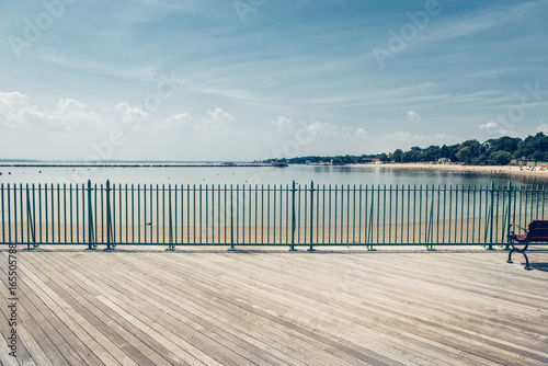 Fotografía Empty ocean beach boardwalk pier at hot summer day against blue sky