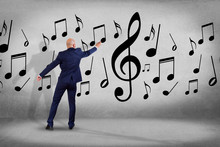 Businessman In Front Of A Wall Writing Music Notes - Art Concept