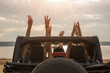 Friends sitting in a car with hands raised