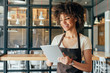© LIGHTFIELD STUDIOS - Young african american woman waitress taking orders from clients in cafe