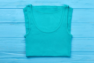 Wall Mural - Turquoise t-shirt for sport activity. Single t-shirt isolated on blue wooden bakground.