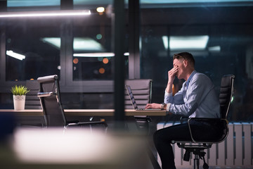 man working on laptop in dark office