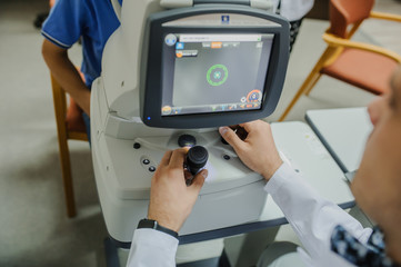 Close up of young beautiful doctor/eye specialist/optometrist in an ophthalmologic clinic dooing a patient a Tomography