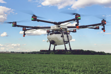 Drone flying above beautiful landscape green field. Hovering drone flies in blue sky and taking pictures of green hills.