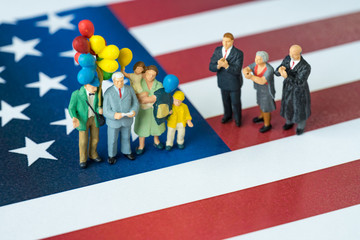 Wall Mural - miniature people celebrate Independence day, man giving speech with happy family holding balloons and United State national flag in the background