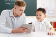 © View Stock - Male teacher helping student study