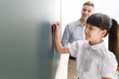 © View Stock - Girl writing on blackboard in classroom, teacher in background