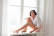 © dmitriisimakov - girl sits at a window in a white room