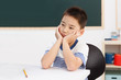 © View Stock - School boy sitting at study desk with hands on chin