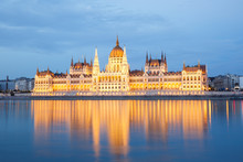 The Building Of Parliament With Reflection In The River In Budapest At Sunset