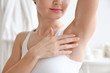 Closeup view of woman touching her armpit on blurred background. Epilation concept
