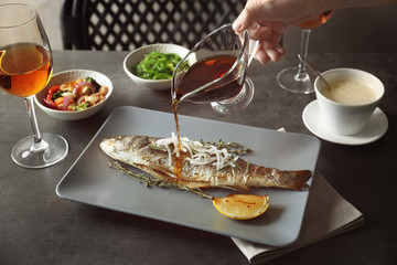 Sticker - Woman's hand pouring sauce onto tasty baked fish on plate