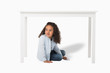 © LIGHTFIELD STUDIOS - adorable african american girl sitting under table isolated on white