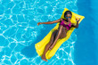 © LIGHTFIELD STUDIOS - African american woman floating with cocktail on inflatable mattress in swimming pool