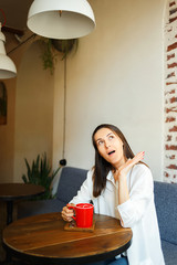 Wall Mural - Red cup of coffee in the hands of a beautiful smiling girl