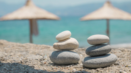 Two pebble towers with sun umbrellas on a sea shore