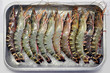 Grilled tiger prawns in a tray of ice on a white background
