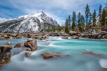 Turquoise Creek With Snowcapped Mountain In Background