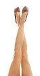 Slim female legs in high heels on white background