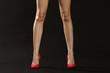 Slim female legs in high heels on dark background
