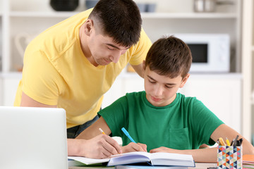 Canvas Print - Father and son doing homework together indoors